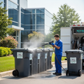 Worker sanitizing commercial waste bins